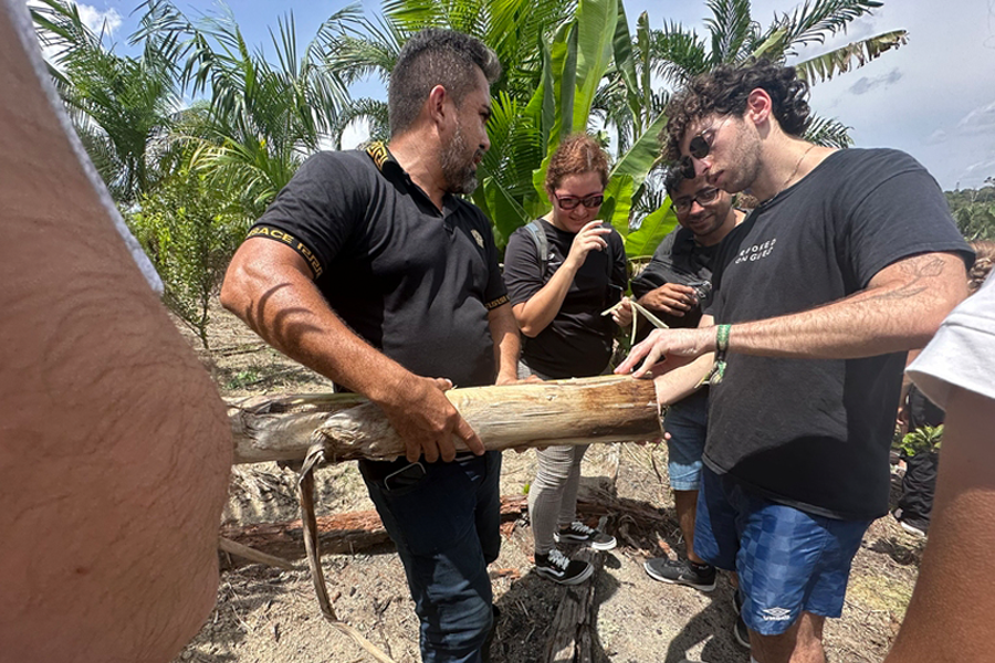 Caption:MIT student Max Siegel (right) examines local vegetation for potential uses.